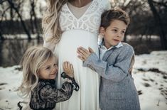 two young children standing next to each other in front of a pregnant woman's belly