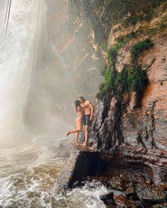 two people standing on the edge of a waterfall