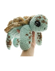 a hand holding up a small stuffed turtle