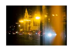 a city street at night with cars driving down it