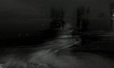 a black and white photo of people walking down the street at night in the rain