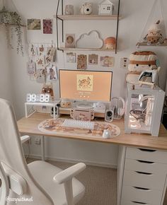 a desk with a computer on it in front of a clock and other items hanging on the wall