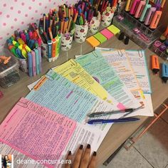 a table topped with lots of different colored pens and paper on top of each other