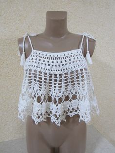 a mannequin wearing a white crochet top with tassels on it