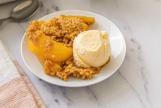 a white plate topped with an ice cream and fruit crumbled on top of it