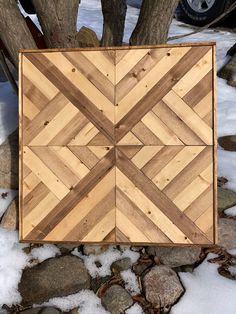 a wooden box sitting on top of snow covered ground next to a tree and rocks