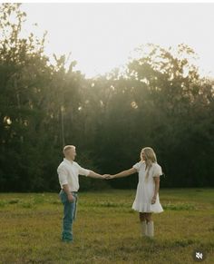 a man and woman holding hands while standing in an open field with the sun behind them