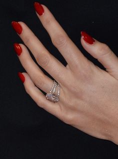 a woman's hand with red nail polish and ring