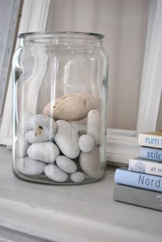 a glass jar filled with rocks sitting on top of a table next to some books