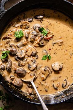 a skillet filled with mushroom soup and garnished with parsley on the side