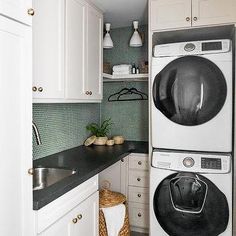 a washer and dryer in a small room with white cabinets, black counter tops