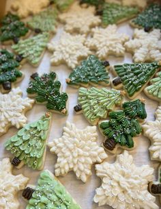 decorated cookies with frosting and decorations are on a sheet of baking paper in the shape of snowflakes