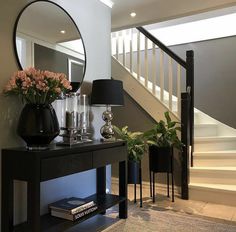 a table with flowers and candles on it in front of a staircase area that has stairs leading up to the second floor