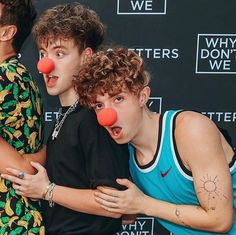 three young men with clown noses posing for a photo at an event in front of a black backdrop