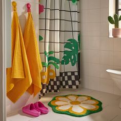 a bathroom with colorful towels hanging on the wall and pink slippers sitting on the floor