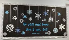 a bulletin board with snowflakes hanging from it's sides and the words be still and know that i am god