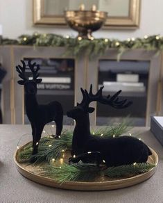 two black deer figurines sitting on top of a table next to a christmas tree