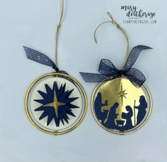 two christmas ornament hanging from strings on a white background with blue and gold trim