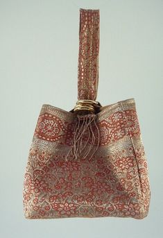 "This elegant silk wristlet measures 5 x 5\" square and has a wristlet strap that loops through gold rings for closure. The lining is a gold silky fabric with sparkles, and the bottom is made out of a coordinating tapestry floral design.The gold fringe adds more detail to the strap.Perfect for those holiday parties coming up or an evening out on the town. Beautiful coral and gold colored silk fabric with small floral patterns in the fabric. Can be made to order in other colors." Gold Fringe, Tapestry Fabric, Coral And Gold, Floral Tapestry, Upcycled Vintage, Sewing Bag, Silk Fabric, Holiday Parties, Making Out