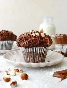 two chocolate cupcakes sitting on top of a white plate next to a bottle of milk