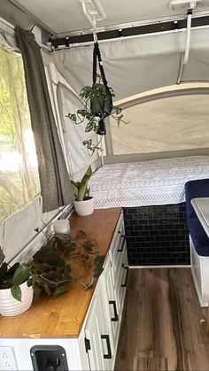 the interior of a small camper with wood flooring and white walls, including a bed