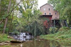 a water mill with a red building in the background