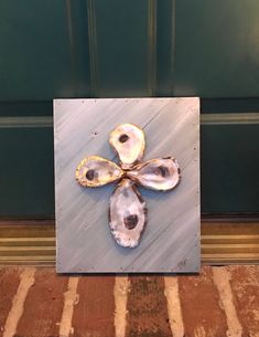 an art piece with three oysters in it on a wooden surface next to a green door