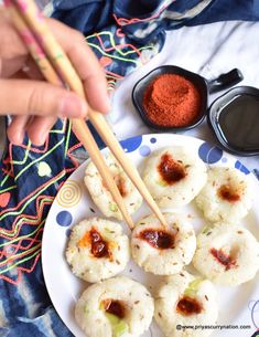 someone holding chopsticks over some food on a plate