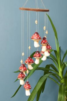 a wind chime with mushrooms hanging from it's sides next to a potted plant