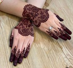 two hands with henna tattoos on them sitting on a wooden floor next to each other