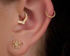 a woman's ear is adorned with two gold - plated hoops and a flower design