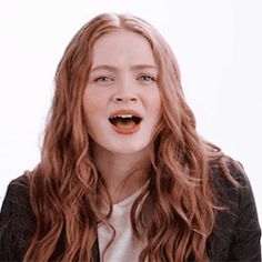 a woman with long red hair is making a funny face while wearing a black jacket