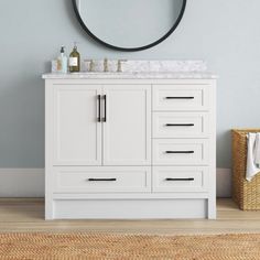 a bathroom vanity with a round mirror above it and a rug on the floor next to it