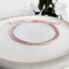 This delicately-strung exclusively crafted bracelet has two strands of tiny Japanese Miyuki glass beads in pink Shell Silk and shiny silver set on natural light pink silk cord. All beads have  a uniform shape with a sparkly finish, perfect for a minimalist look that can be dressed up or down. Finished with a macramé sliding clasp to adjust to your size. **New** Now available with Silver or Gold beads. Please select from variations Also available in Gold/Shell or Turquoise/Copper - https://www.et Small Jute Bags, Copper Glass, Dainty Bracelet, Holiday Essentials, Silk Cord, Jute Bags, Bracelets Handmade Beaded, Glass Beaded Bracelets, Dainty Bracelets