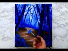 someone is painting a forest scene with blue paint