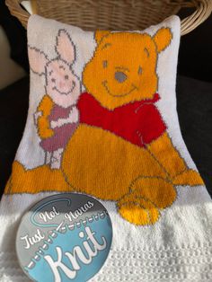 a winnie the pooh and piglet pillow sitting next to a basket