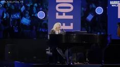 a woman sitting at a piano in front of a crowd