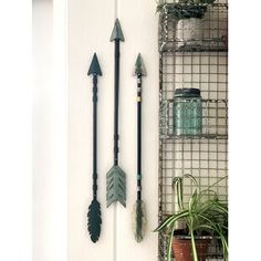 three metal arrows hanging on the side of a white door next to a potted plant