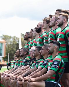 a group of rugby players sitting next to each other on the sidelines with their hands in their pockets