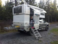 a man sitting in the back of a truck with a camper attached to it