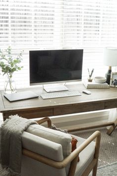 a desk with a computer and chair in front of it, next to a window