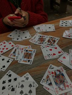 playing cards are scattered on the table and someone is holding a cell phone in their hand