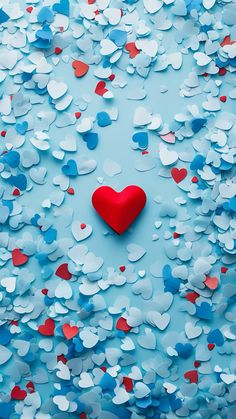 a red heart surrounded by confetti on a blue background with white and red hearts