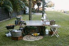 an outdoor picnic table is set up in the grass with food and drinks on it