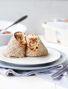 two burritos sitting on top of a white plate next to a bowl of salsa