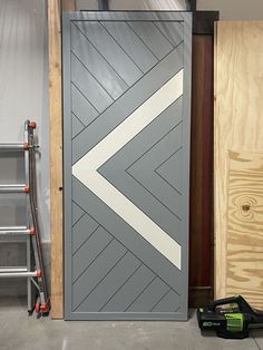 a gray door with white arrows painted on it and tools next to it in a garage