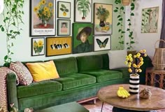 a living room filled with green couches and pictures on the wall above them, surrounded by potted plants