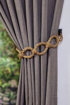 a curtain with rope attached to it next to a window