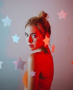 a woman with stars painted on her face in front of a backdrop that looks like she is looking at the camera