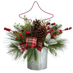 a christmas arrangement with pine cones, holly and berries in a galvanide bucket